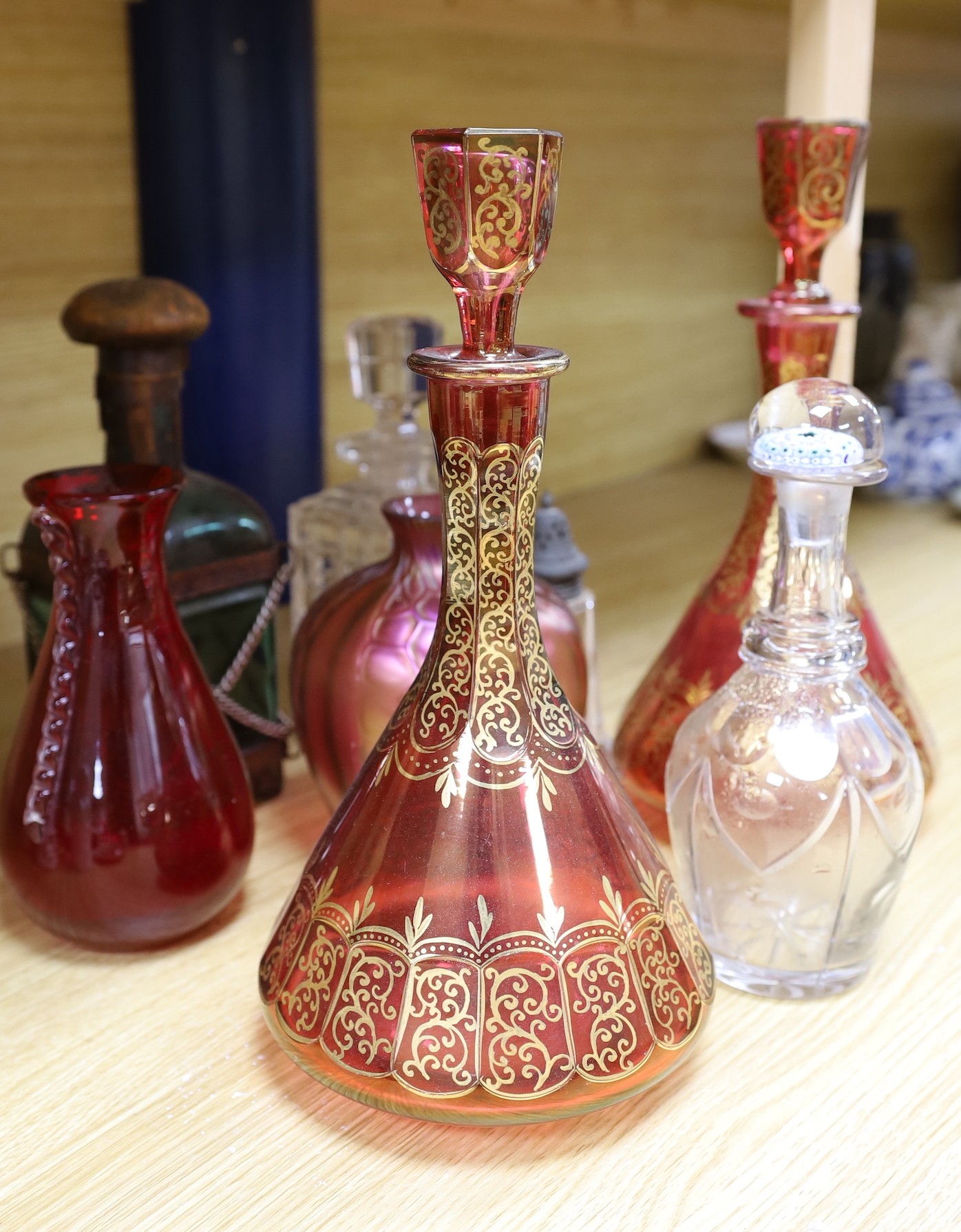 A pair of Bohemian gilded ruby glass decanters and stoppers, a Bohemian ‘millefiori paperweight’ stopper and associated decanter and mixed glass